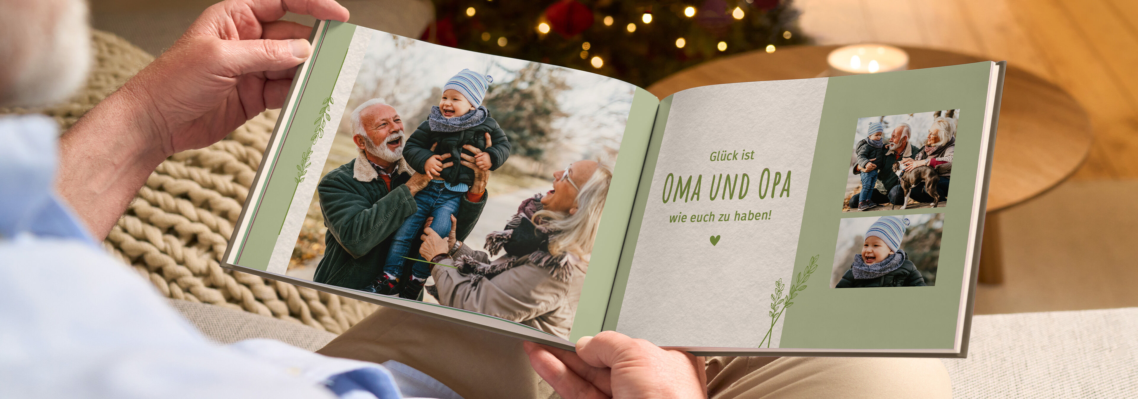 Person betrachtet ein CEWE FOTOBUCH mit Familienfotos und dem Schriftzug „Glück ist OMA UND OPA wie euch zu haben!“ vor einem Weihnachtsbaum