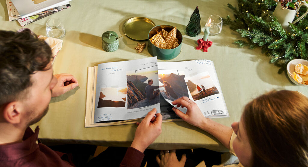 Ein Pärchen klappt gemeinsam die ersten Seiten einer Panoramaseite in einem CEWE FOTOBUCH auf.