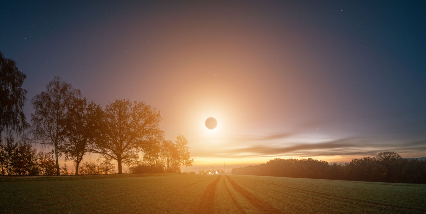 Tiefstehende Sonnenfinsternis über einer ländlichen Umgebung.